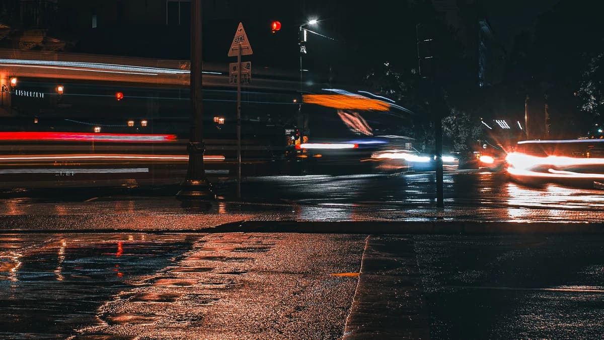 Car lights moving through a wet street in Buenos Aires at night